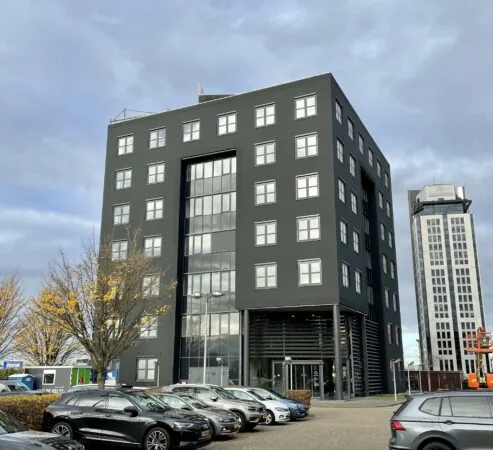 Zwart kantoorgebouw aan het Rivium Quadrant met geparkeerde auto's op de voorgrond.